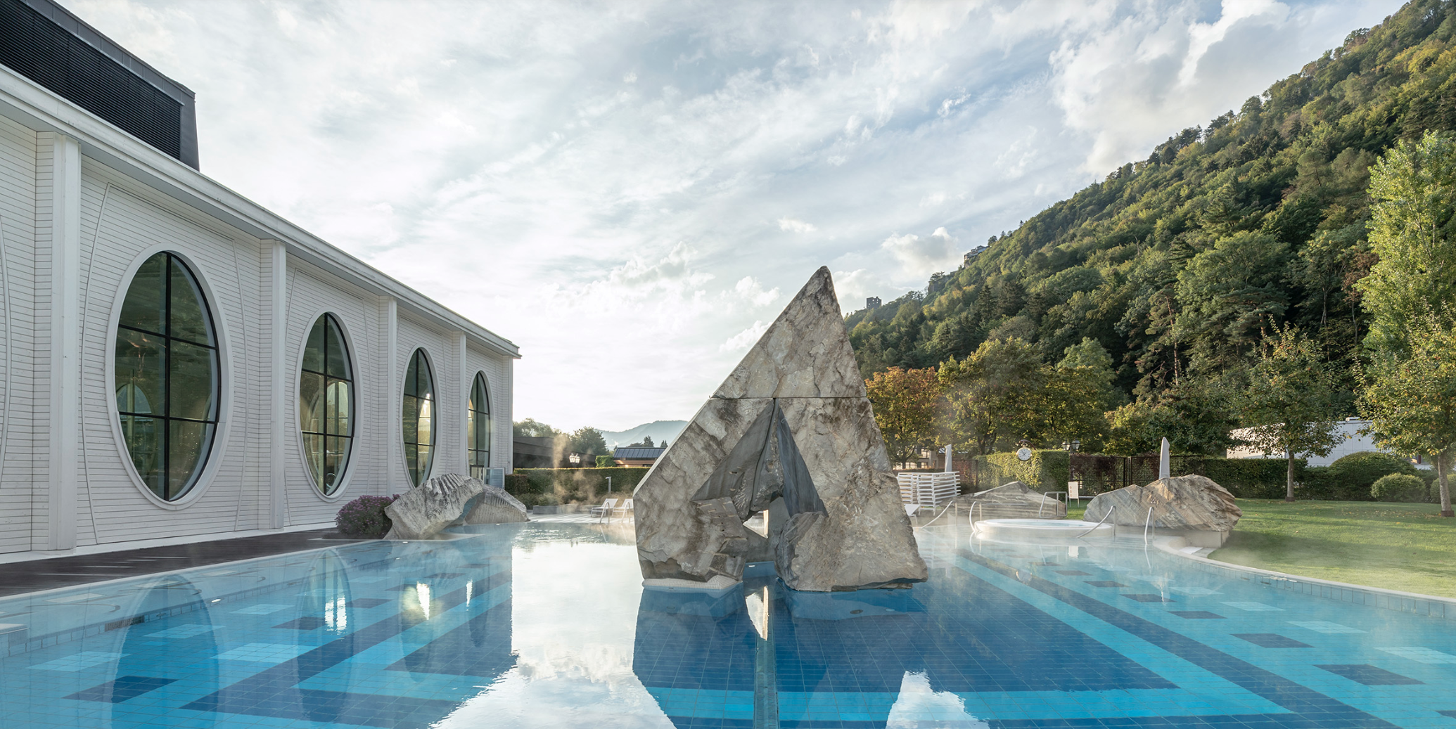 Modern luxury pool with sculptural stone features and mountain views